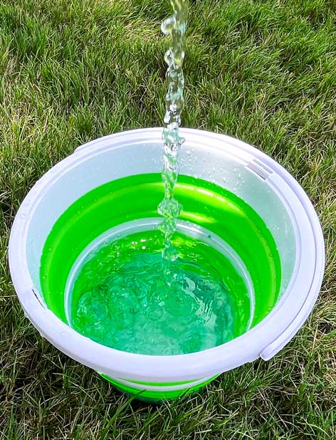 Water being poured into a green and white bucket